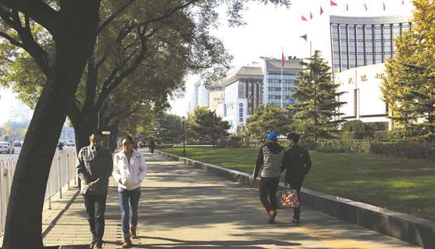 Pedestrians walk past the Peopleu2019s Bank of China headquarters (right) in Beijing. The PBoC is drafting a package of reforms which would give foreign investors greater access to the nationu2019s financial services industry.