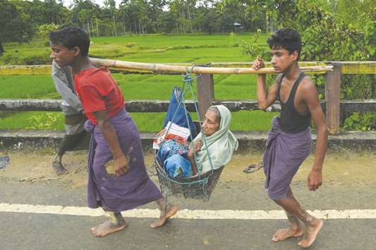 Rohingya Muslim refugees carry an elderly woman along a road near Balukhali refugee camp near the Bangladehsi district of Ukhia yesterday.