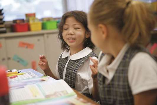 BACK TO CLASS: Sophia Trujillo, 8, looks over to classmate Giuliana Gallo, 8, during religion class on her first day of third grade at St. Philip the Apostle Catholic School in Addison, Illinois.