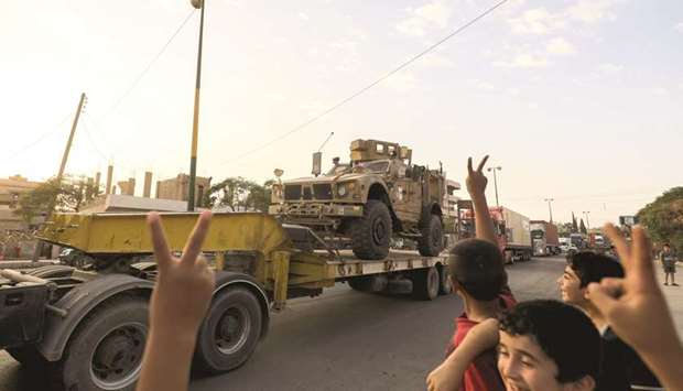 Children flash the victory gesture as a military convoy carrying US-made vehicles, bulldozers and arms headed for Syrian Democratic Forces (SDF) fighting in Raqqa, passes through the  northeastern city of Qamishli yesterday.