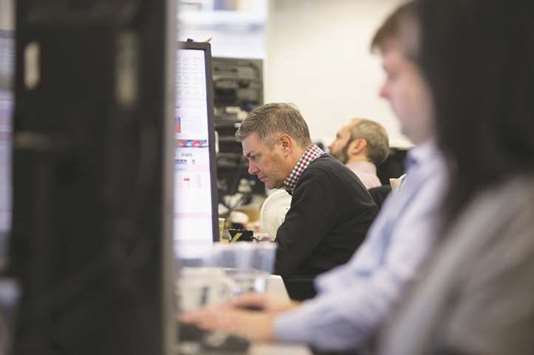 Traders study information on trading screens at ETX Capital in central London. The worldu2019s stock markets all but froze yesterday as few investors had the nerve to invest fresh money before a long-awaited interest rate call from the Federal Reserve later in the day.