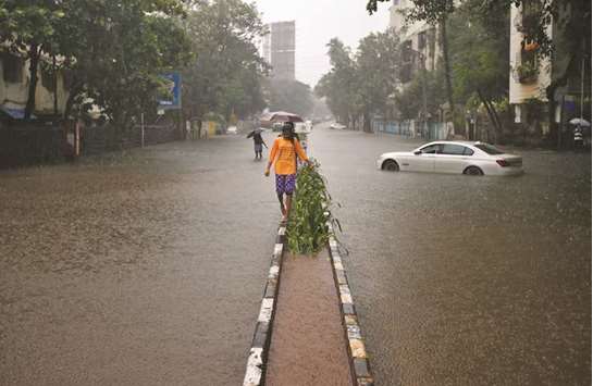A girl walks on a road divider in a water-logged street during heavy rains in Mumbai yesterday.