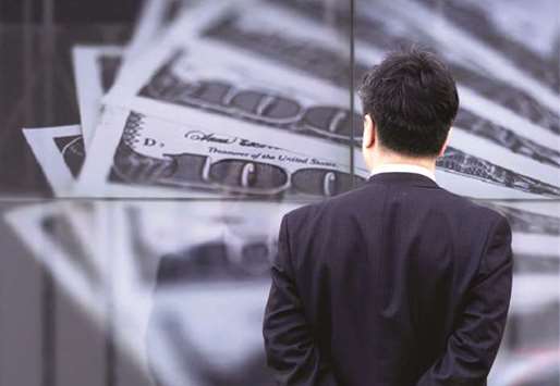 A businessman looks at a screen displaying a photo of $100 banknotes in Tokyo (file). The dollar fell back against the euro yesterday but firmed against the yen, as markets assessed the Federal Reserveu2019s outlook for US interest rates.