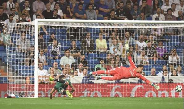 Real Betisu2019 forward from Paraguay Arnaldo Sanabria heads the ball to score a goal as Real Madridu2019s goalkeeper from Costa Rica Keylor Navas dives to save it during the La Liga match at the Santiago Bernabeu stadium in Madrid. (AFP)