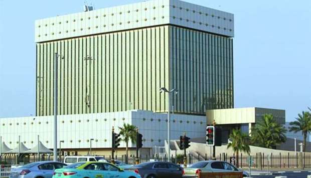 Cars drive past the Qatar Central Bank building in Doha. Qatar has sufficient resources to support its dollar peg, according to the EIU.