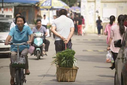 A man pulls a basket of leeks as he walks along a road near an open market in Beijing (file). The downgrade, the second by a major ratings company this year, represents ebbing international confidence that China can strike a balance between maintaining economic growth and cleaning up its financial sector.