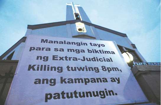 A sign is posted outside a Catholic church which translates to u201cLet us pray for the victims of extrajudicial killings, bells will toll at 8:00pmu201d in Quezon City, Metro Manila, yesterday.