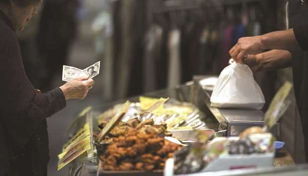 A woman holds a u00a51,000 bank note as she buys food at a shopping street in Kitakyushu, Fukuoka, Japan (file). Headline inflation, includes changes in food and energy prices, while core inflation leaves those items out because theyu2019re prone to short-term spikes.