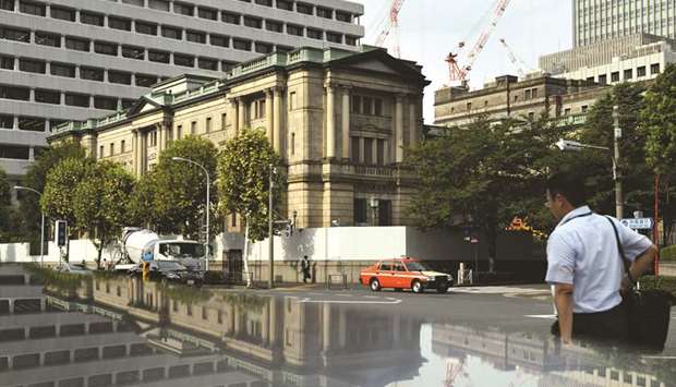 Pedestrians walk past the Bank of Japan headquarters in Tokyo on September 13. With the Bank of Japan leaving its unprecedented monetary easing programme intact on Thursday, S&P said pressure on lending margins may intensify.