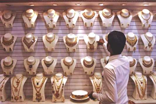 A shopkeeper displaying gold jewellery articles at his shop in Lahore.