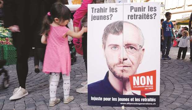 A child passes a poster promoting the vote on pension reform.