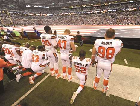 The Cleveland Browns team stand and kneel during the National Anthem before the start of their game against the Indianapolis Colts at Lucas Oil Stadium in Indianapolis.