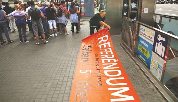 Catalan National Assembly member and Terrassa town hall staffer Pep Rovira rolls up a banner after Catalan Mossos du2019Esquadra officers prohibited his protest yesterday in favour of the banned October 1 referendum at Catalunya square in Barcelona. The banner reads u2018Referendum. Where everything starts. 5 days leftu2019.