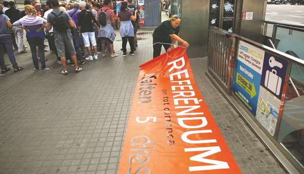 Catalan National Assembly member and Terrassa town hall staffer Pep Rovira rolls up a banner after Catalan Mossos du2019Esquadra officers prohibited his protest yesterday in favour of the banned October 1 referendum at Catalunya square in Barcelona. The banner reads u2018Referendum. Where everything starts. 5 days leftu2019.