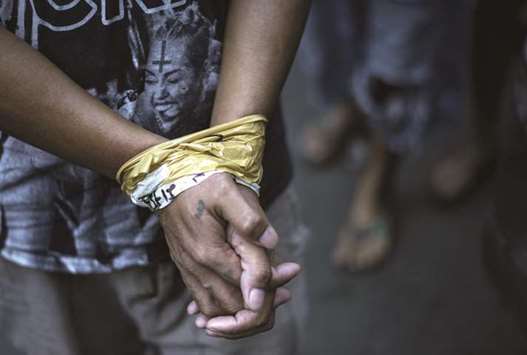 File photo shows a man with his hands bound as male residents are rounded up for verification after police officers conducted a large scale anti-drug raid at a slum community in Manila.