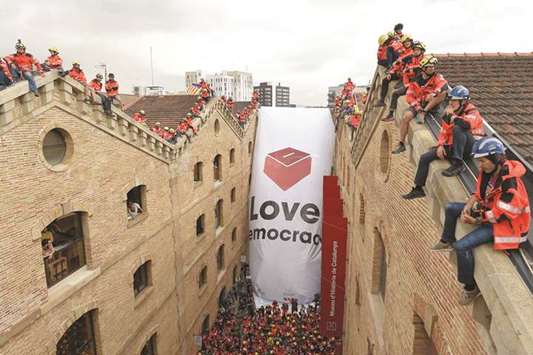 Catalan firefighters unfurl a banner depicting a ballot box and reading u2018Love Democracyu2019 in front of the Museum of History of Catalonia in Barcelona.
