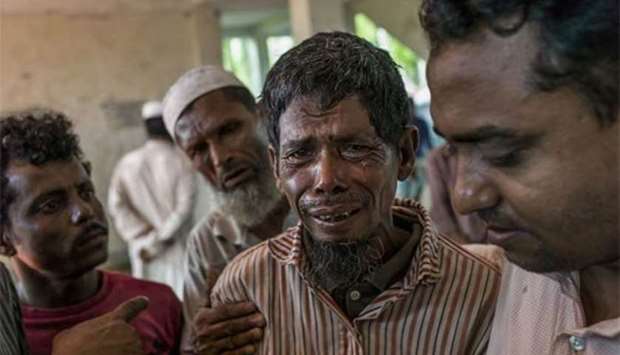 Rohingya refugee mourn beside bodies at a school near Inani beach in Cox's Bazar district on Friday.