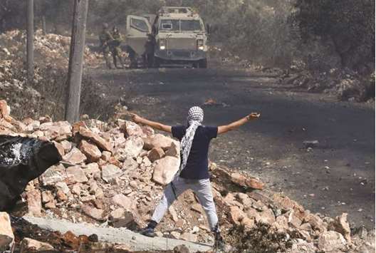 A Palestinian protester gestures in front of Israeli troops during clashes near the settlement of Qadomem, in the West Bank village of Kofr Qadom near Nablus, yesterday.