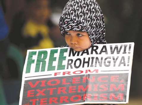 A young Muslim girl holds a placard after noon prayers for the Marawi siege and the plight of Rohingyas, in Quezon City, Metro Manila.