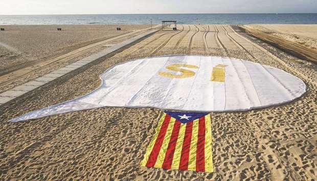 An Estelada (Pro-independence Catalan flag) beside a banner reading u201cSIu201d (Yes) is unfurled yesterday on El Masnou beach, near Barcelona during an action called by Catalan National Assembly to support a referendum on independence in Catalonia.