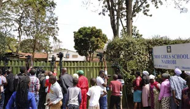 Media and people locked out by police wait at the entrance of Moi Girls School in Nairobi where a blaze gutted one of the boarding facilities.