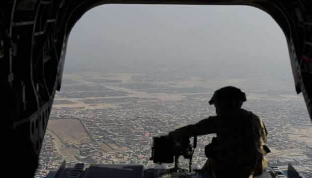 A US soldier sits in the rear of Chinook helicopter while flying over Kabul.
