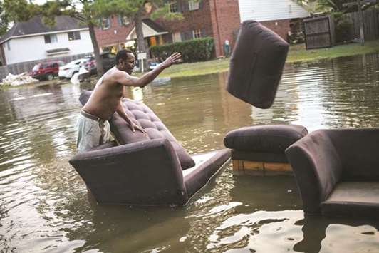 Vince Ware moves his sofas onto the sidewalk from his house which was left flooded from Tropical Storm Harvey in Houston.