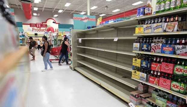 Customers walk near empty shelves that are normally filled with bottles of water after Puerto Rico Governor Ricardo Rossello declared a state of emergency in preparation for Hurricane Irma, in San Juan on Monday.