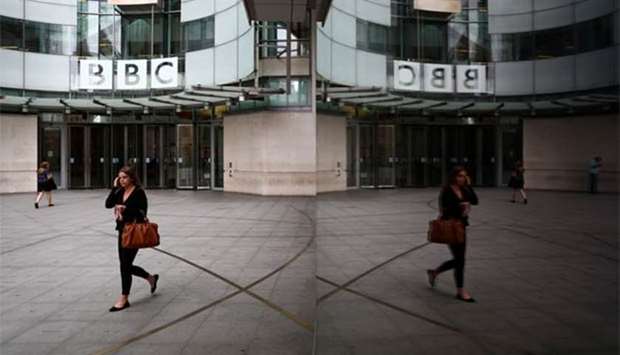 A woman is reflected as she passes the BBC's Broadcasting House in London.