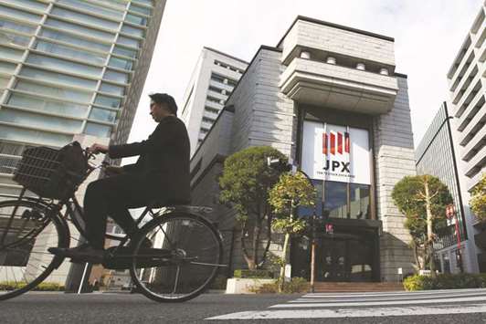 A man cycles past the Tokyo Stock Exchange. Foreign investors are ditching Japanese stocks, as worries about a rising yen eclipse the brightest earnings season in years, an economy brimming with vigour and business confidence at its highest since before the global financial crisis.