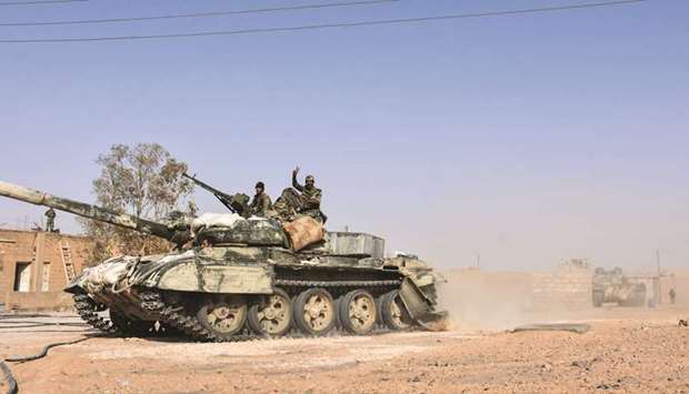 Members of the Syrian government forces raise the victory gesture as they ride on an advancing tank in the village of Kobajjep, on the southwestern outskirts of Deir Ezzor province, yesterday, during the ongoing battle against Islamic State (IS) group militants.