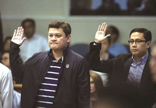 Davao City Vice Mayor Paolo Duterte (left) and Manases Carpio take an oath as they attend a senate hearing in Manila.