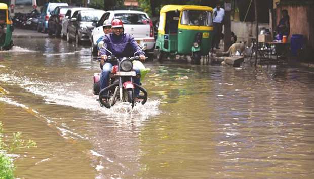 A biker makes his way through a water-logged street after rains lashed Bengaluru yesterday.