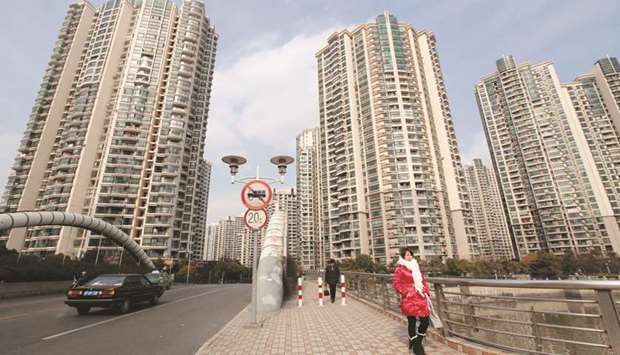 Women walk in front of a housing complex in Shanghai. Property developers accounted for 72% of the $28.5bn of Chinese junk-rated bond sales this year, according to data compiled by Bloomberg.