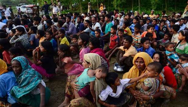 Rohingya people wait for relief supplies near a refugee camp