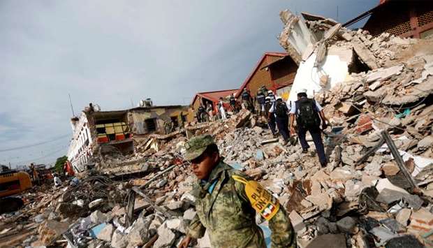 Soldiers work to remove the debris of a house destroyed in an earthquake that struck off the southern coast of Mexico