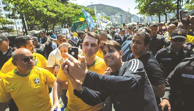Flavio Bolsonaro poses for a selfie with a supporter of his father, right-wing presidential candidate Jair Bolsonaro, during a rally at Copacabana beach in Rio de Janeiro, Brazil, yesterday.
