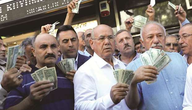 Businessmen holding US dollars stand in front of a currency exchange office in response to the call of Turkish President Tayyip Erdogan on Turks to sell their dollar and euro savings to support the lira. The withholding tax on foreign currency deposits of up to six months is raised from 18% to 20%, while tax on deposits of up to one year is hiked from 15% to 16%, under the decision that came into force yesterday.