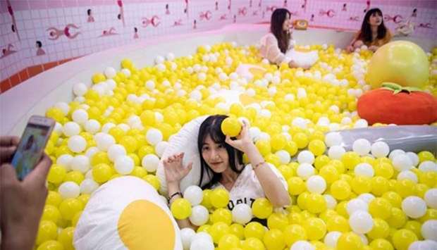 A visitor poses for a photograph inside a giant caviar bowl at the Egg House in Shanghai.