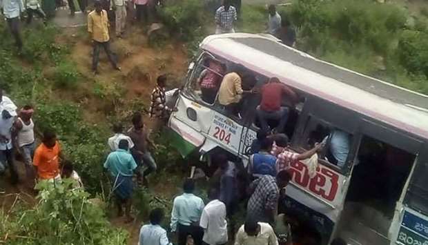 Onlookers and rescuers gather around a bus that crashed in Jagtial district in India's southern Telangana state