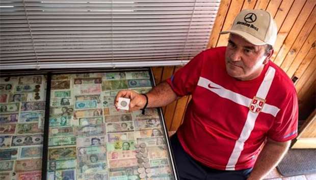 Serb Zoran Milosevic holding his latest addition, a coin from Bermuda, at his home in Pavlovci, 70 km west of Belgrade.