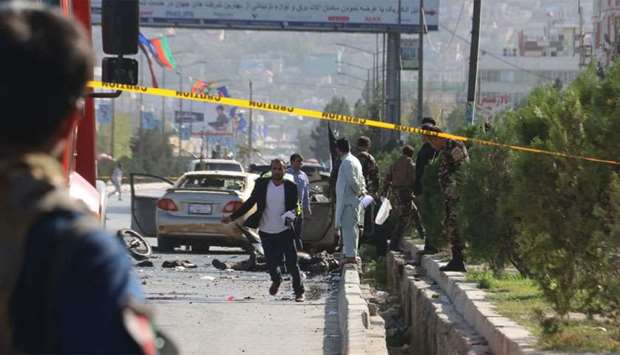 Afghan security personnel inspect a site following a suicide attack
