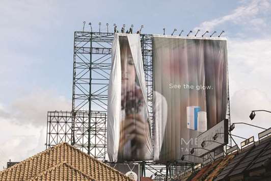 Workers roll advertising billboards along main road EDSA in preparation for the coming of super typhoon Mangkhut before it hits the main island of Luzon, in Quezon City, Metro Manila, yesterday.