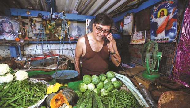 A vegetables vendor speaks on his phone as he waits for customers at a market in Mumbai. Indiau2019s consumer prices rose 3.69% from a year earlier, down from Julyu2019s 4.17%, the statistics ministry said yesterday.
