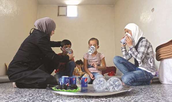 Um Majid (left) tries an improvised gas mask on family members in her home in Binnish in Syriau2019s rebel-held northern Idlib province as part of preparations for any upcoming raids, yesterday.