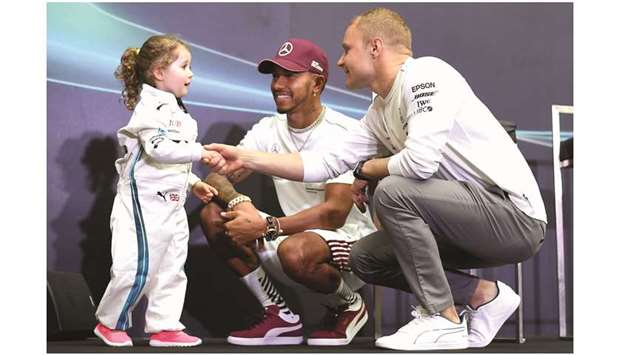 Mercedesu2019 British driver Lewis Hamilton (centre) and Mercedesu2019 Finnish driver Valtteri Bottas speak with three-year-old fan Leila during a u2018meet and greetu2019 event at a shopping mall ahead of the Singapore Formula One Grand Prix in Singapore yesterday. (AFP)