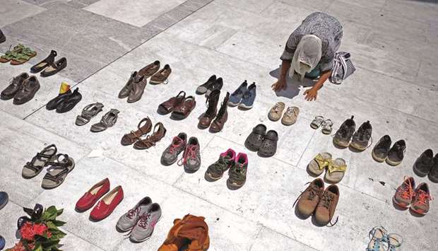 This June 1 file photo shows a woman praying in front of hundreds of shoes that were displayed in memory of those killed by Hurricane Maria in front of the Puerto Rican Capitol, in San Juan.