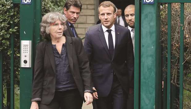 French President Emmanuel Macron walks with Michele Audin, daughter of the late Maurice Audin, as he leaves the home of Josette Audin, widow of Audin, in Bagnolet yesterday.