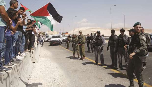 Demonstrators wave Palestinian flags in front of Israeli troops as they protest against Israelu2019s plan to demolish the village of Khan al-Ahmar, in the occupied West Bank, yesterday.