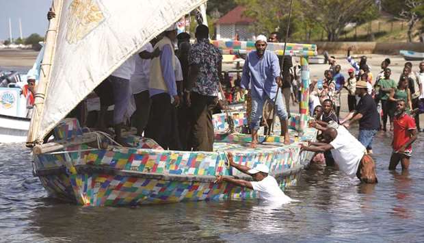 People push Flipflopi into the water for its first voyage on the island of Lamu, Kenya.